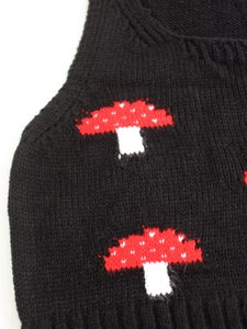 Detail of black knit vest featuring woven red and white mushroom jacquard pattern