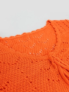 Detalle del top de punto calado naranja con cuello de volantes y textura de ganchillo