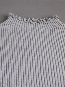 Detail of ribbed knit grey sweater showing the ruffled neckline and premium texture