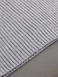 Close-up of light gray ribbed knit fabric texture showing professional finish and weave