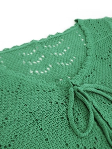 Detalle de top de punto calado verde brillante con lazo decorativo en el cuello y patrón