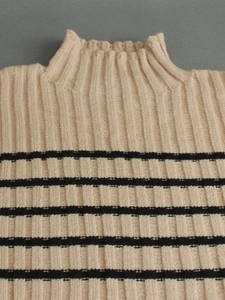 Detail of ribbed knit texture on a beige mock neck sweater with black stripes