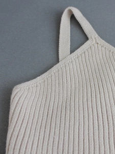 Close-up of beige ribbed knit texture and seam detail on a V-neck camisole top