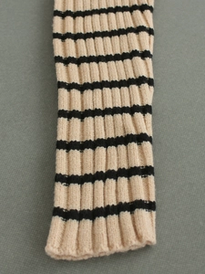 Detail of ribbed knit texture on striped long sleeve sweater showing beige and black patterns