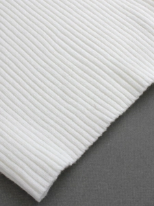 Gros plan sur la texture du tricot blanc côtelé montrant une élasticité et douceur premium