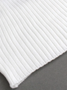 Détail du tissu en maille côtelée blanche montrant sa texture douce et élastique