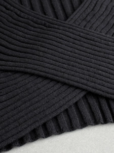 Close-up of black ribbed knit fabric showing the texture and layered cross design