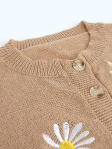 Detail of camel knit cardigan showing marble resin buttons and white daisy embroidery