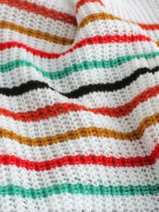 Detailed macro shot of multi-color rainbow knit fabric with breathable hollow weave pattern