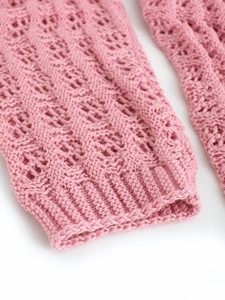 Gros plan d'un cardigan rose en maille montrant les détails délicats du motif au crochet