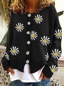 Detail of white daisy floral embroidery on black knitted cardigan with large round buttons