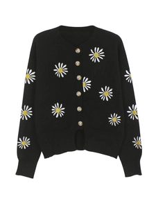 Close-up of black knit cardigan featuring detailed white daisy embroidery and brown buttons