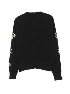 Detail of white daisy embroidery on the sleeves of a black knit sweater cardigan