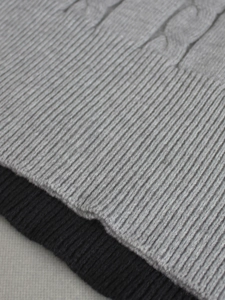 Nahaufnahme von Rippbündchen und Zopfmuster bei grauem und schwarzem Strickpullover