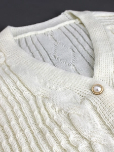 White cable knit cardigan sweater with V-neck and decorative pearl button detail