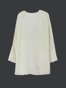 Detailed close-up of soft white knitted sweater texture and ribbed cuff design