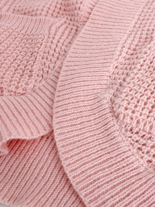 Close-up detail of soft pink waffle knit fabric with ribbed edging on women cardigan