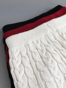 Dettaglio della trama a treccia del set tre pezzi in nero, rosso vino e beige crema