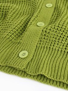 Detail of green waffle knit cardigan showing thick texture and matching resin buttons