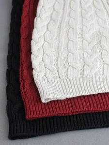 Dettaglio della trama a trecce su set in maglia nei colori bianco, rosso e nero