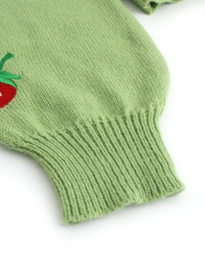 Detailed view of ribbed cuff and red strawberry embroidery on light green knitted cardigan