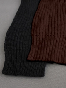Detailed close-up showing the ribbed knit texture and cuff of black and brown beach sweaters