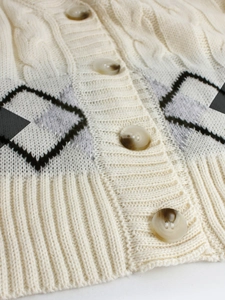 Close-up of cable knit cardigan with marbled buttons and argyle pattern texture
