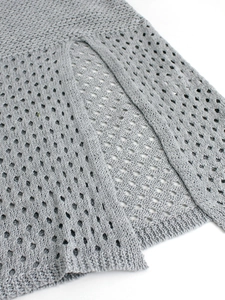 Detailed close-up of light grey crochet knit fabric with diamond hollow out pattern