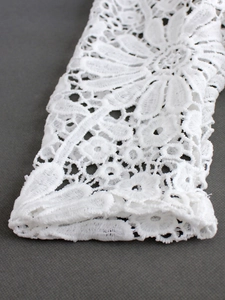 Detailed close-up of white lace knit sweater featuring intricate floral hollow embroidery