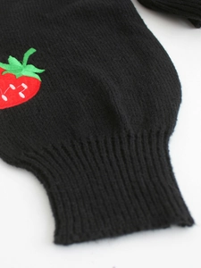 Detail shot of black knitted cardigan cuff with vibrant red strawberry embroidery