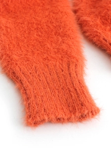Detailed macro view of vibrant orange long-pile knit sweater cuffs with soft texture