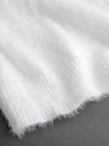 Detailed macro view of soft white mohair knit fabric with ribbed hemline texture