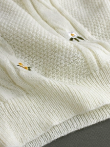 Creamy white crewneck knit sweater featuring intricate cable knit and floral embroidery
