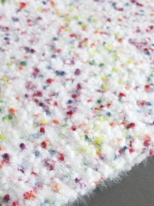 Macro shot of fluffy white knit fabric with colorful vibrant dots for soft home decor