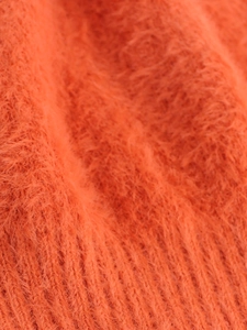 Macro shot of bright orange long-hair plush knit fabric with soft mohair texture