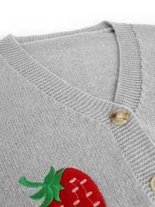 Close-up of strawberry embroidery on grey knitted cardigan with cream button detail