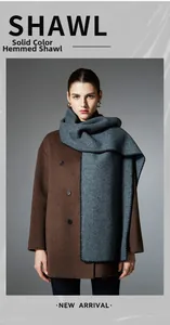 Detail of dark grey solid scarf with whipstitch edges worn with a brown wool coat