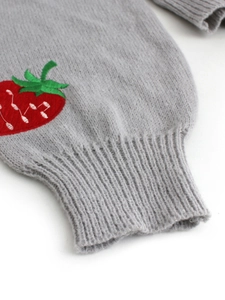 Detail of ribbed cuff on gray knitted cardigan with red strawberry embroidery