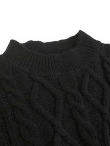 Close-up of black cable knit sweater featuring a ribbed crew neck and soft wool texture