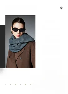 Detail of dark grey knit scarf with decorative stitching paired with a wool coat