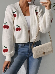 Close-up of white knit cardigan featuring detailed red cherry embroidery and V-neckline