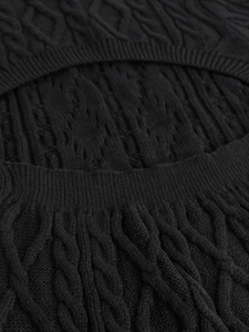 Close-up of black cable-knit dress showing intricate diamond pattern and texture