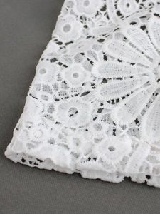 Close-up of intricate white lace floral embroidery with hollow-out knit detailing