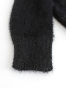 Close-up of black fuzzy knit sweater sleeve featuring ribbed cuffs and soft plush texture