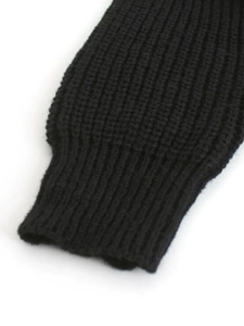 Dettaglio del pullover in maglia nera con polsini a costine strette e trama a maglia grossa
