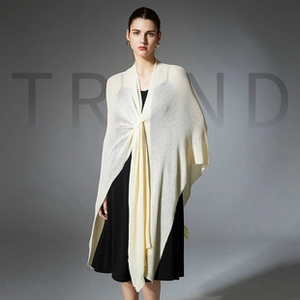 Close-up of cream knit shawl with a front twist knot over a black evening dress