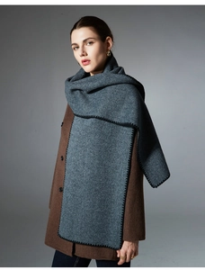 Macro detail of dark grey wool scarf with decorative black whipstitch edge on model