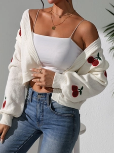 Close-up of intricate red cherry embroidery on white knit long sleeve cardigan