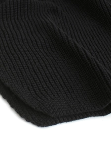 Dettaglio del maglione nero con scollo a V che mostra la trama a coste e il tessuto