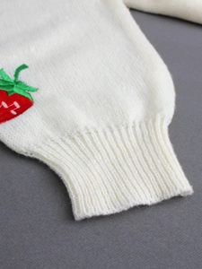 Detailed view of white knit cardigan ribbed cuff with red strawberry floral embroidery